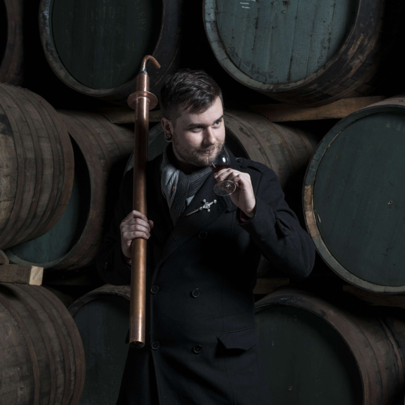 Photo of Garrett studying a whisky blend at a distillery in Scotland